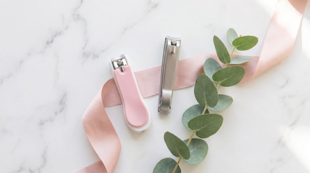 Cortaúñas de manicura rosa y cortaúñas de pedicura metálico Fussy sobre mármol