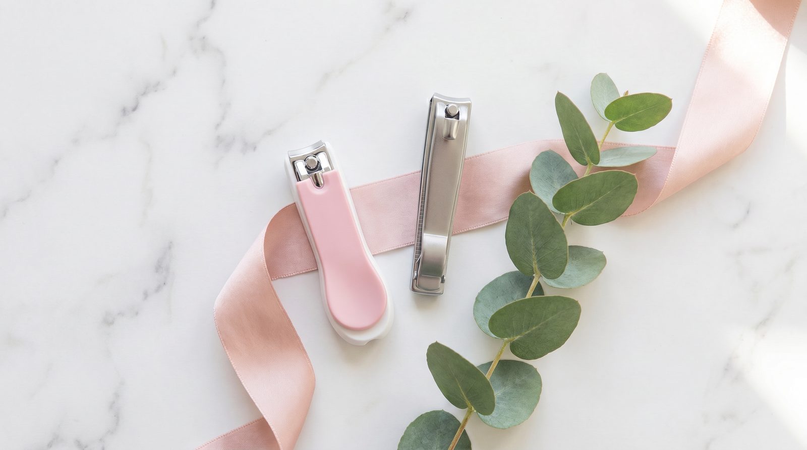Cortaúñas de manicura rosa y cortaúñas de pedicura metálico Fussy sobre mármol